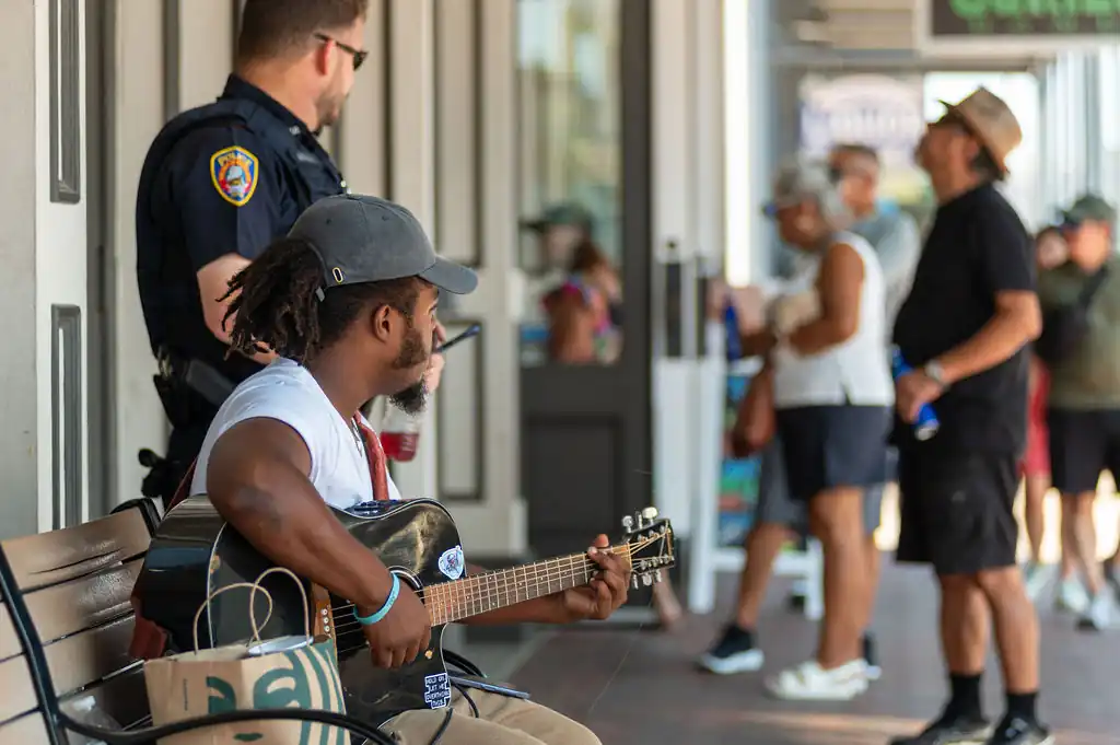 Man playing guitar on street bench in coastal Texas town, representing the vibrant culture of Gulf communities