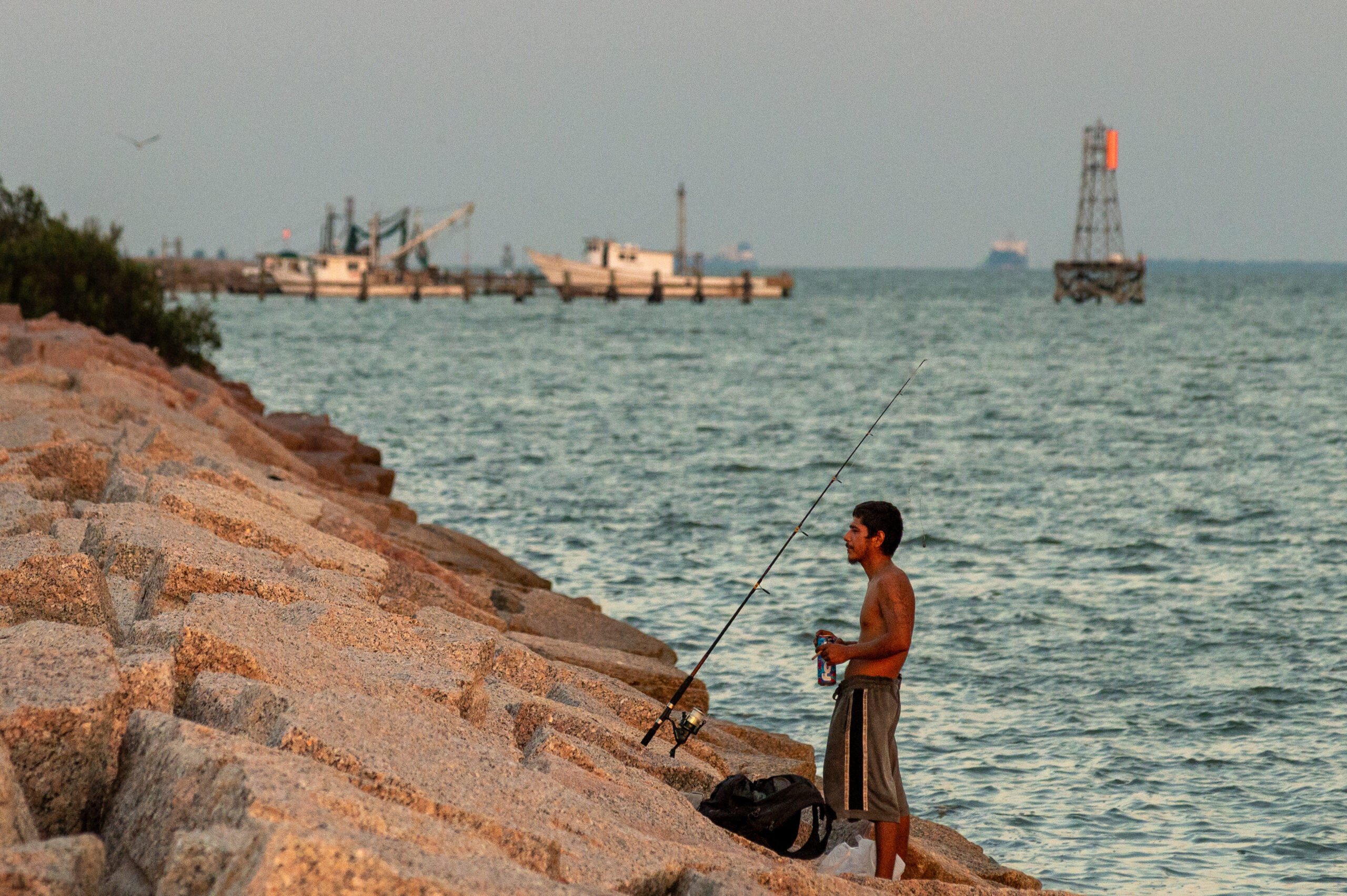 Image of Texas coast with man fishing off a jetty