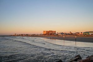 People enjoy the beach at sunrise. Hotels and restaurants on the Strand by the Gulf of Mexico, Galveston, Texas, USA